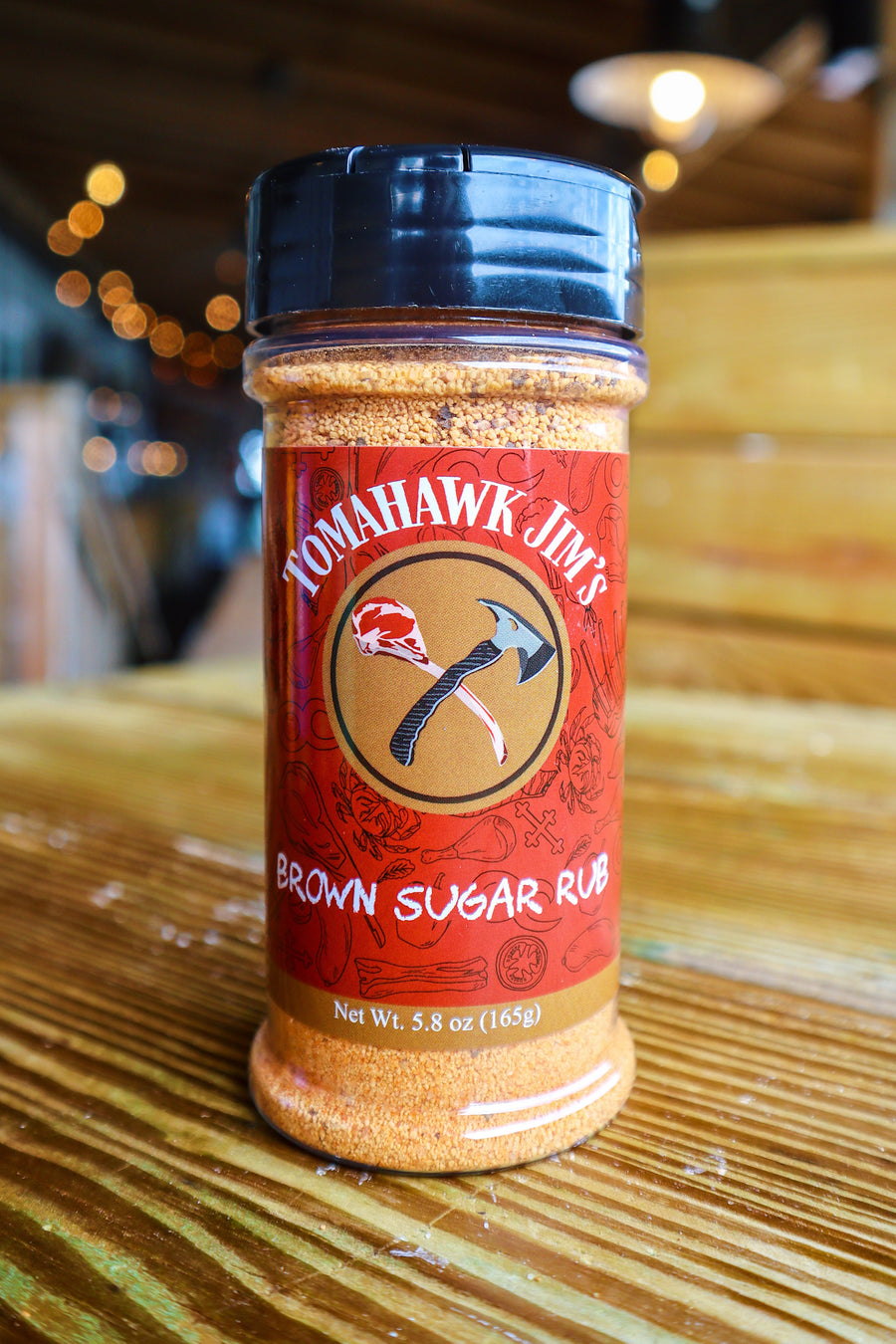 Tomahawk Jim's Brown Sugar Rub spice container on a wooden surface